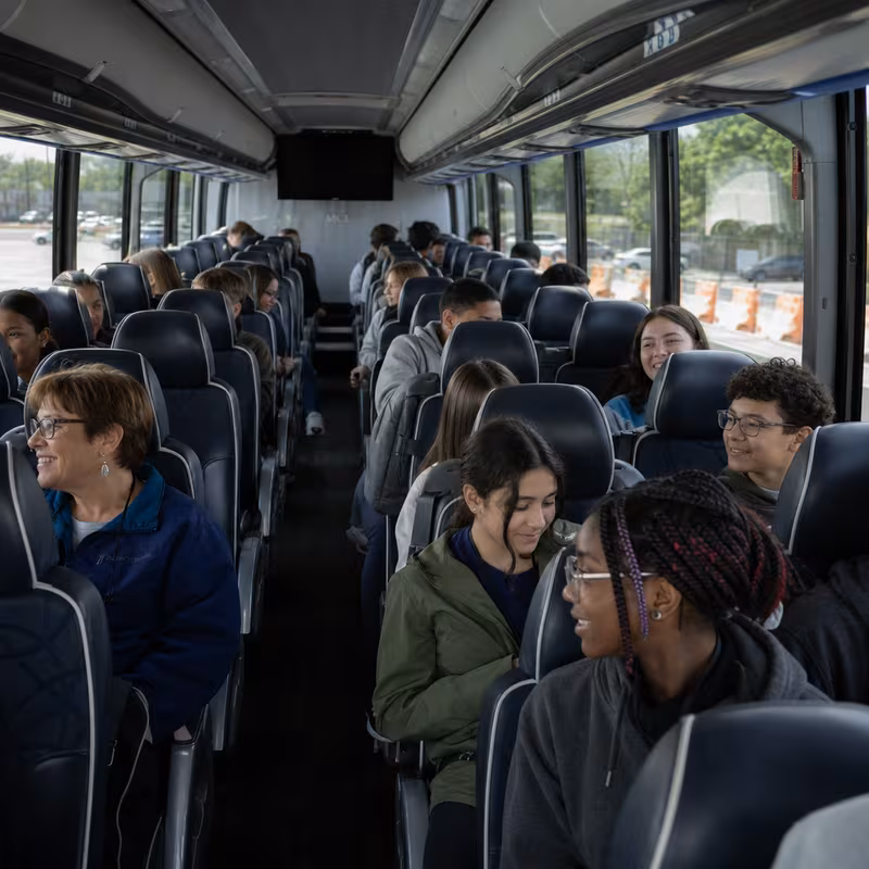 Group boarding a white charter bus for School Transportation transportation in Glendale